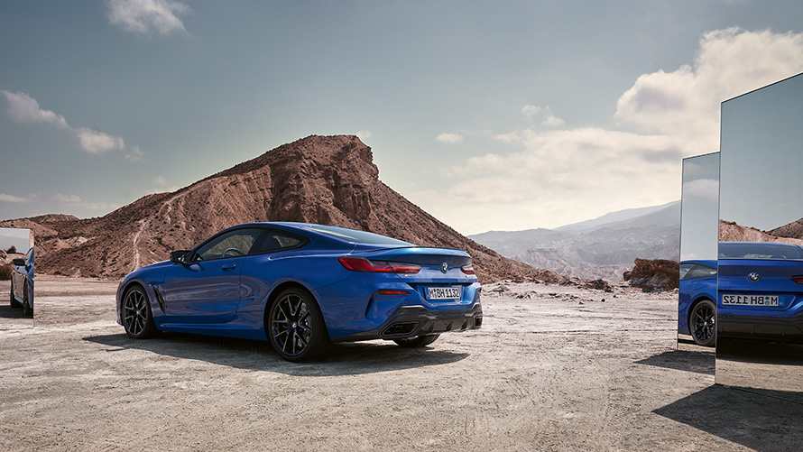 The BMW M850i xDrive Coupé G15 LCI Facelift 2022 M Portimao Blue metallic rear view standing with mirrors