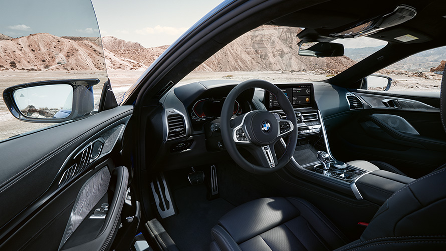 The BMW M850i xDrive Coupé G15 LCI Facelift 2022 Driver-oriented cockpit with M leather steering wheel with open front door