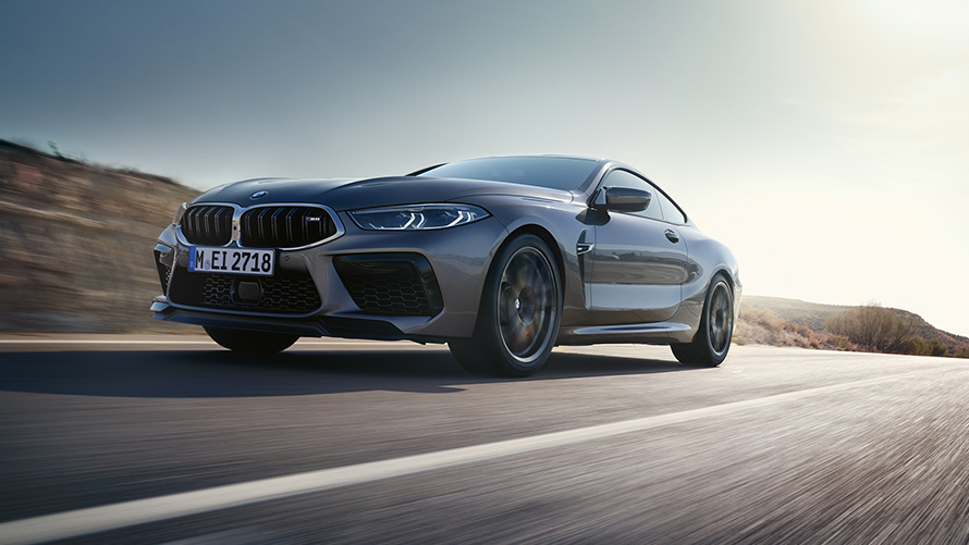 The BMW M8 Coupé F92 LCI Facelift 2022 Skyscraper grey metallic three-quarter front view driving on a highway low angle shot