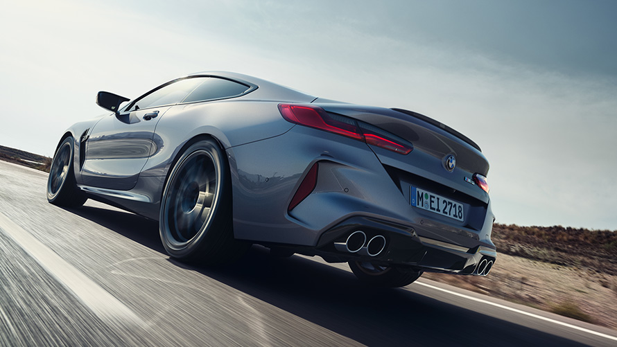 The BMW M8 coupe F92 LCI facelift 2022 Skyscraper grey metallic three-quarter rear view driving on a highway low angle shot