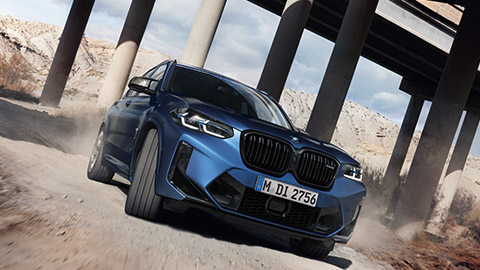 منظر أمامي ثلاثي الزوايا للسيارة BMW M Series BMW X3 M F97 أثناء القيادة