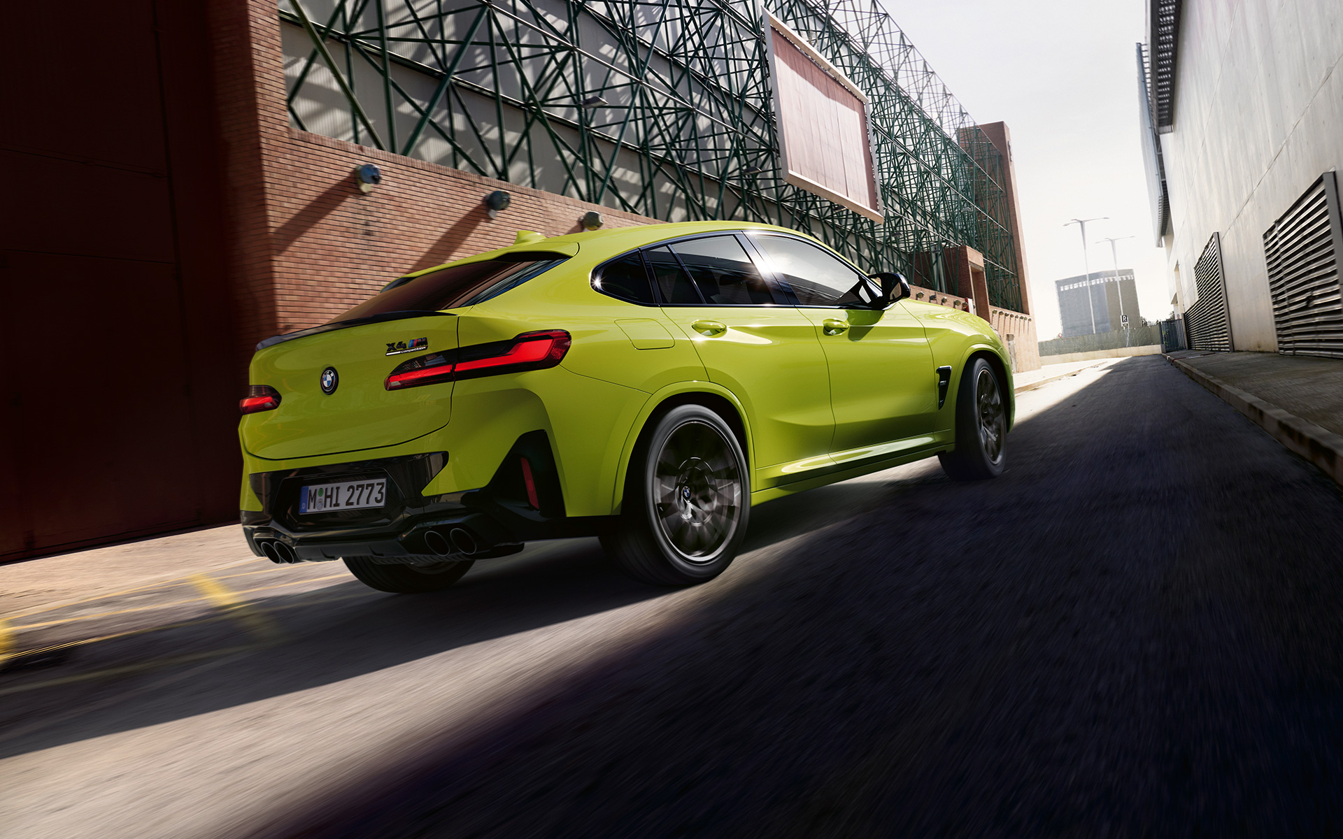 أثناء القيادة بين بنايات المصنع، مشهد جانبي من الزاوية الأمامية لسيارة BMW X4 M Competition F98 LCI Facelift 2021  بلونها الأصفر في ساو باولو بعد إجراء التعديلات على مظهرها 