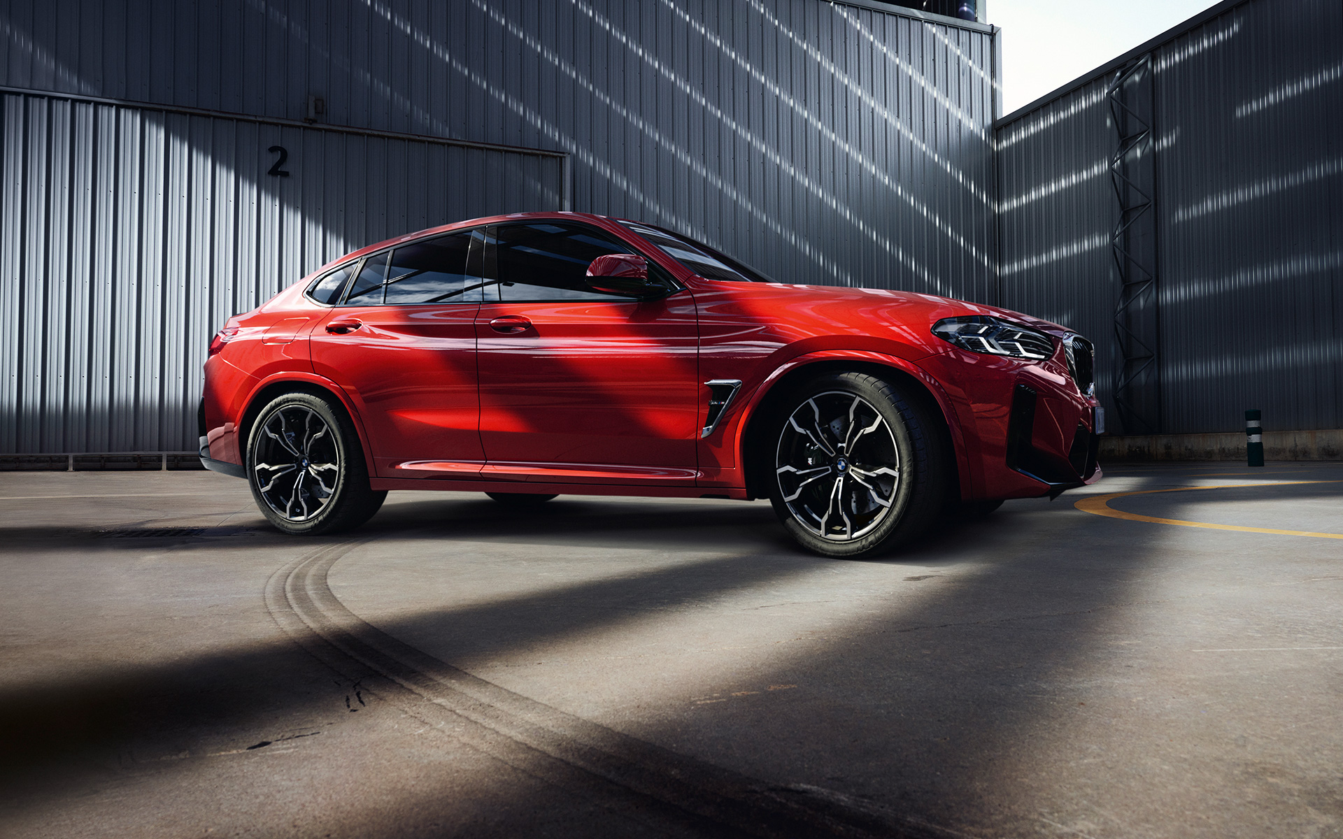 الزاوية الجانبية للسيارة BMW X4 M F98 LCI Facelift 2021 داخل بناية المصنع بلون أحمر معدني تورنتو 