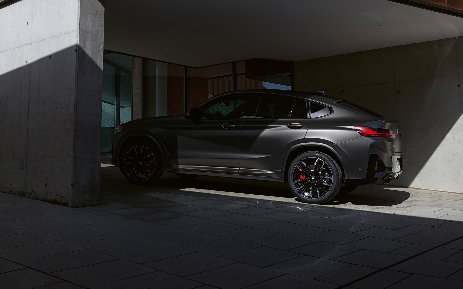 الزاوية الجانبية للسيارة BMW X4 M40i G02 LCI 2021 Facelift التي يغطي الظل نصفها أمام مدخل منزل