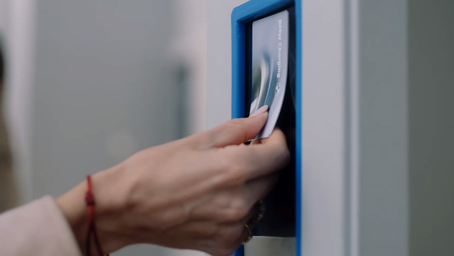 شخص في محطة شحن عامة يضع بطاقة حلول الشحن BMW Charging لشحن السيارة  